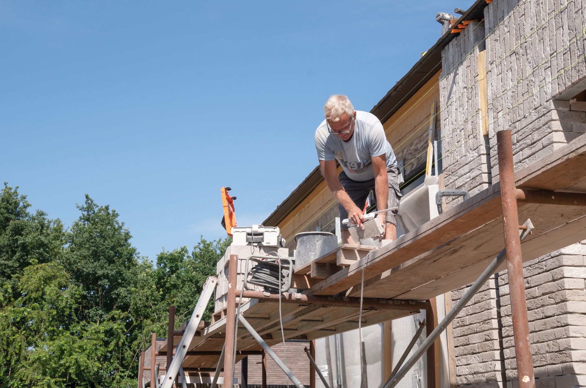 masonry worker the bricklayer makes the facade of the house from gray bricks